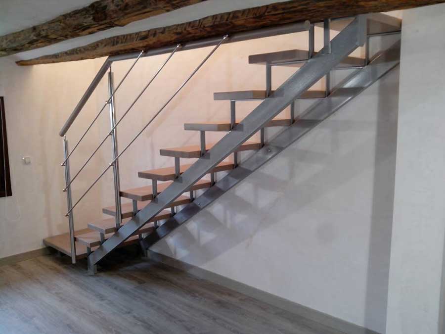 Escalera de líneas limpias en madera y metal. Un diseño ligero que combina a la perfección con las antiguas vigas de madera en esta casa de Sabiñánigo